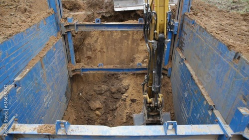 The excavator operator selects the soil from the trench, the walls of which are reinforced with trench supports. The support protects the walls from collapsing and save the workers.