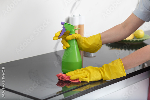 Close up shot of female hands holding bottle spray and rag for cleaning the stove