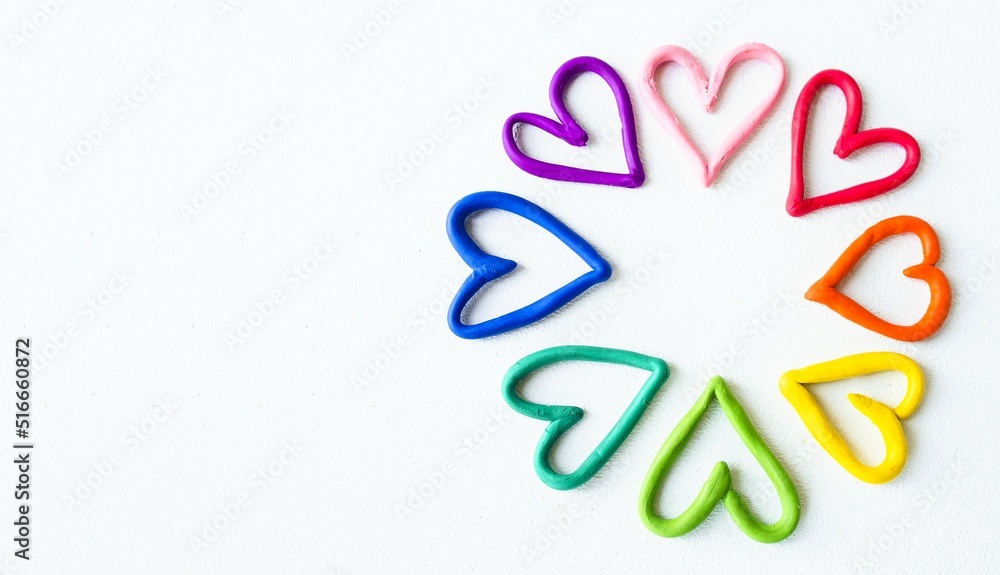 Banner on a white isolated background in the right corner are multi-colored hearts made of plasticine, the colors of the rainbow. Lgbt symbol, gender equality. Close-up. Banner on a white isolated background in the right corner are multi-colored hearts made of plasticine, the colors of the rainbow. Lgbt symbol, gender equality. Close-up.