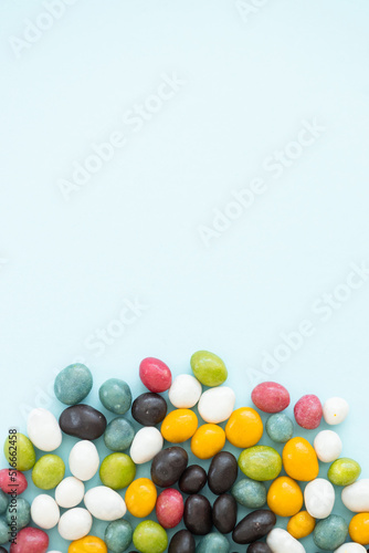 Fototapeta Naklejka Na Ścianę i Meble -  Colorful coated chocolate candies scattered on blue background
