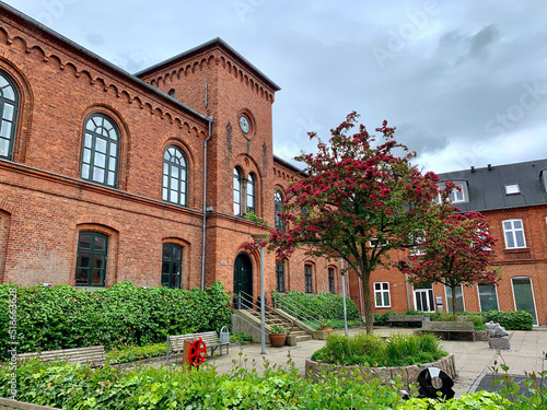 Beautiful historic red brick building of the music school in Lemvig with forecourt, red flowering trees, Lemvig, West Jutland, Denmark