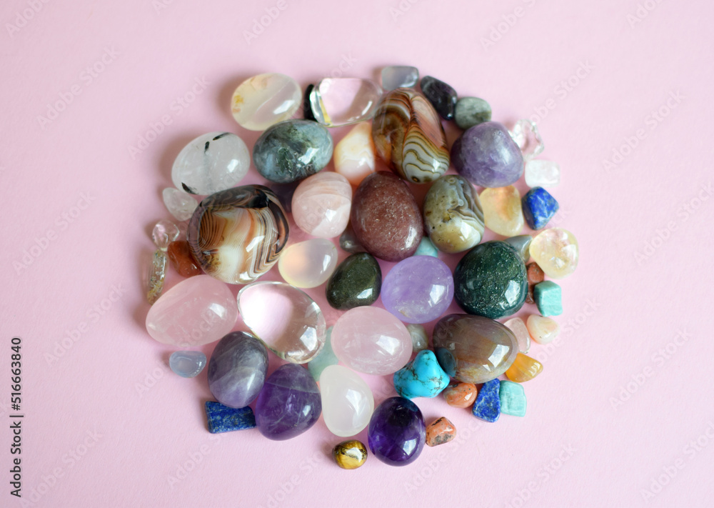 Gems of different colors. Amethyst, rose quartz, agate, apatite, aventurine, olivine, turquoise, aquamarine, rhinestone lie on a pink background. Top view Gems of different colors. Amethyst, rose quartz, agate, apatite, aventurine, olivine, turquoise, aquamarine, rhinestone lie on a pink background. Top view