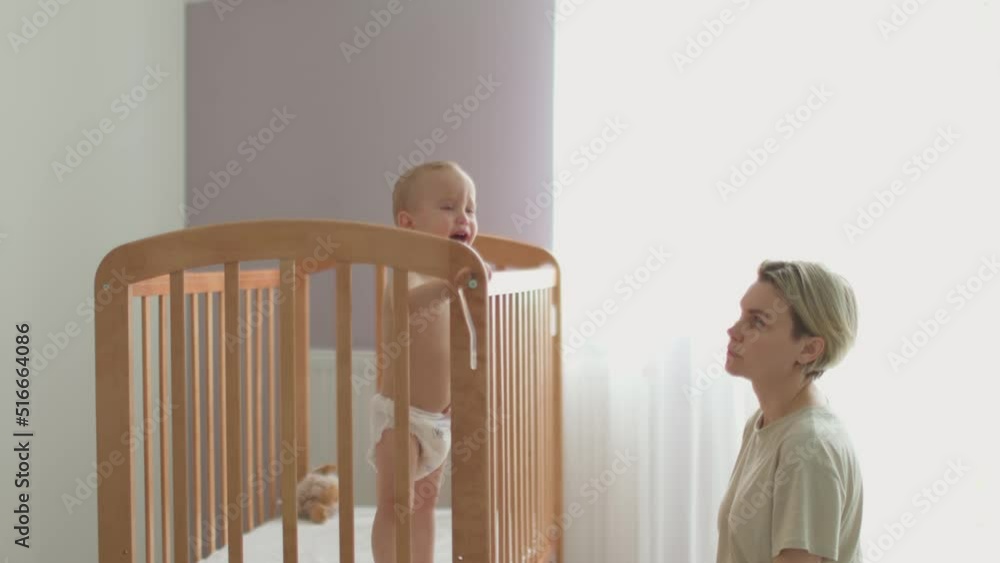 mother trying calm screaming crying baby toddler infant in crib put to