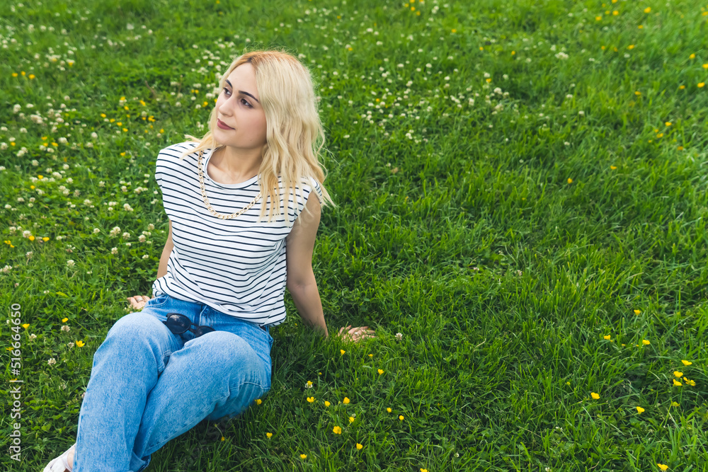 Fototapeta premium blond Caucasian girl resting on the green grass and looking up. medium full shot. High quality photo