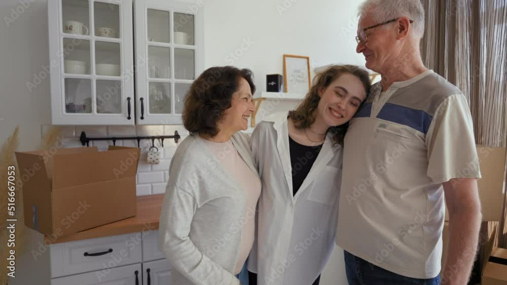 Senior parents give key to new apartment to smiling daughter. Happy young woman hugs elderly mom and dad feeling thankful for gift standing in kitchen Senior parents give key to new apartment to smiling daughter. Happy young woman hugs elderly mom and dad feeling thankful for gift standing in kitchen