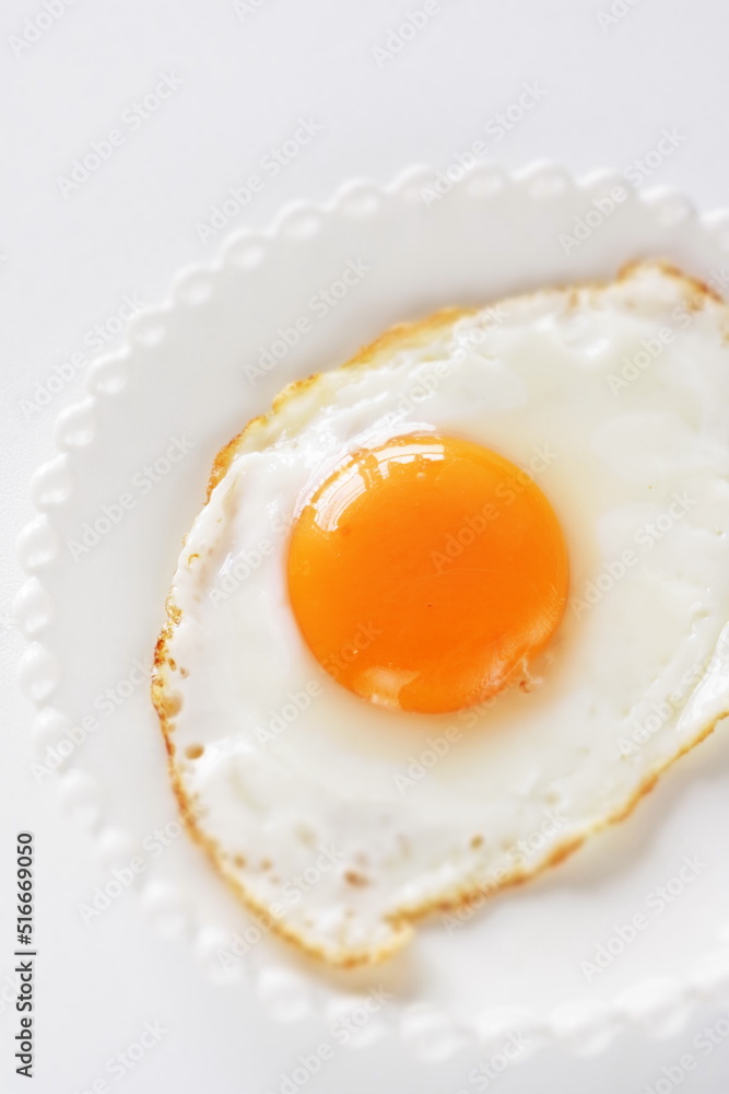 Homemade comfort food, sunny side up fried egg on white plate Homemade comfort food, sunny side up fried egg on white plate