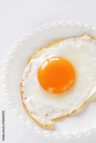 Homemade comfort food, sunny side up fried egg on white plate