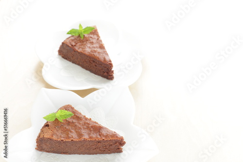 Piece of homemade chocolate cake on white dish with mint