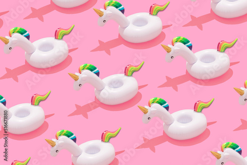 Creative art minimal aesthetic. Inflatable unicorn pool toy pattern on pastel pink background. Minimal summer concept with trendy summer shadows.
