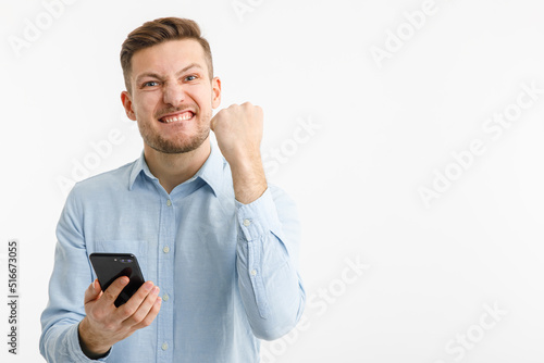 A man holds a smartphone in his hand and rejoices at a successful transaction on crypto exchanges. Isolated on a white background.