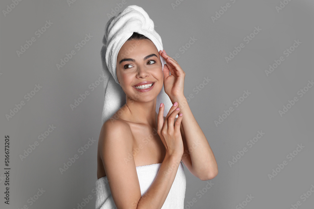 Beautiful young woman with towels on grey background Beautiful young woman with towels on grey background
