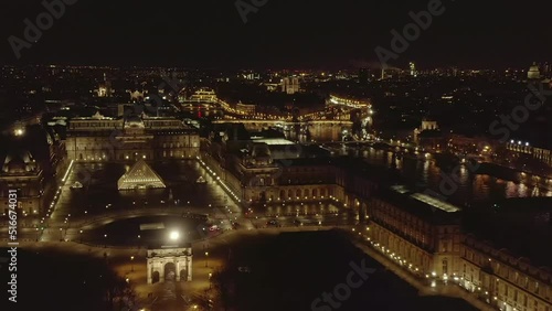 Fly above Louvre Museum of art buildings complex at night. Illuminated square with glass pyramid. Paris, France photo