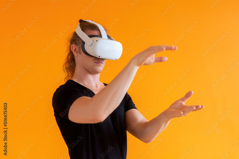 Young man using virtual reality headset. Isolated on orange background. Young man using virtual reality headset. Isolated on orange background.