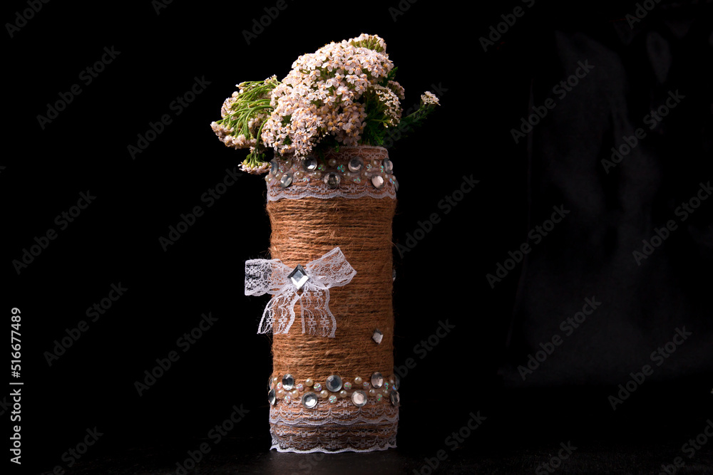 Bouquet of yarrow flowers in a vase on a black background