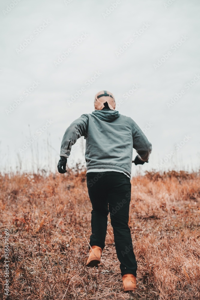A scary looking man with a mask holding a blade running up a hill. A scary looking man with a mask holding a blade running up a hill.