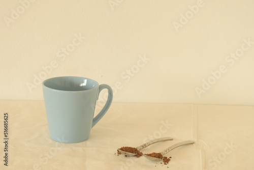 blue coffee cup with two spoons of  instant coffee on white warm background