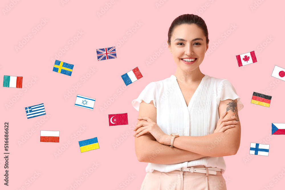 Beautiful young woman and different flags on pink background. Studying of foreign languages Beautiful young woman and different flags on pink background. Studying of foreign languages