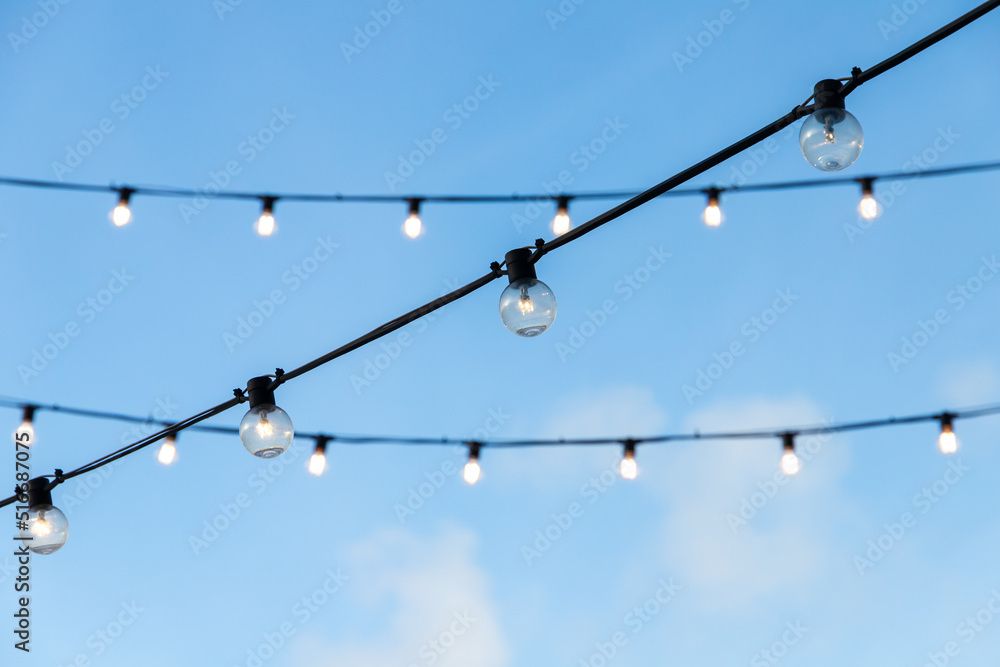 Street garlands of light bulbs hanging on black wires Street garlands of light bulbs hanging on black wires