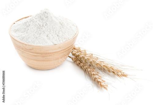 Bowl of flour and wheat ears on white background