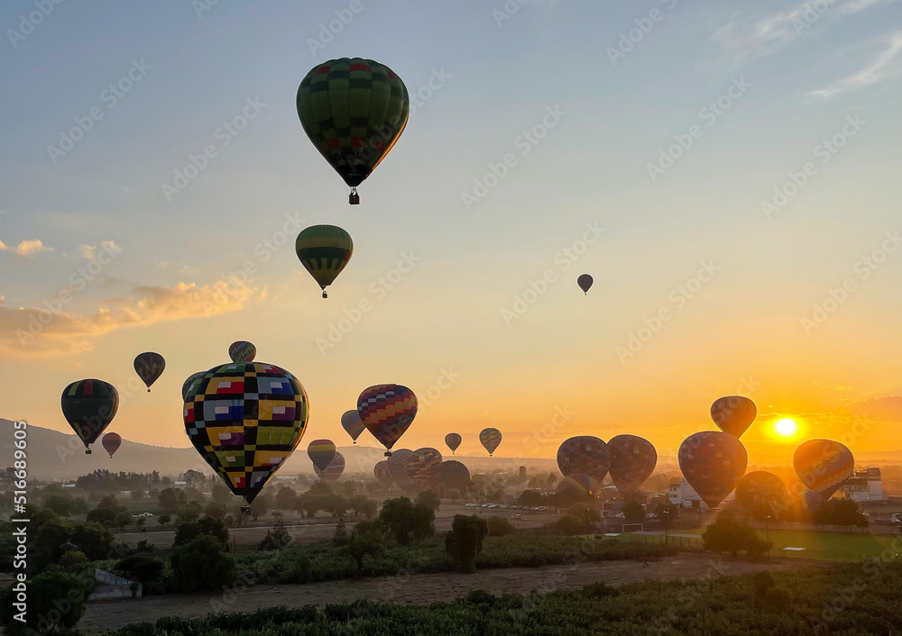 Obraz premium Colorful Hot Air Balloons Flying Over Ancient Pyramid of Teotihuacan, Mexico at sunrise -sunset, over the mist