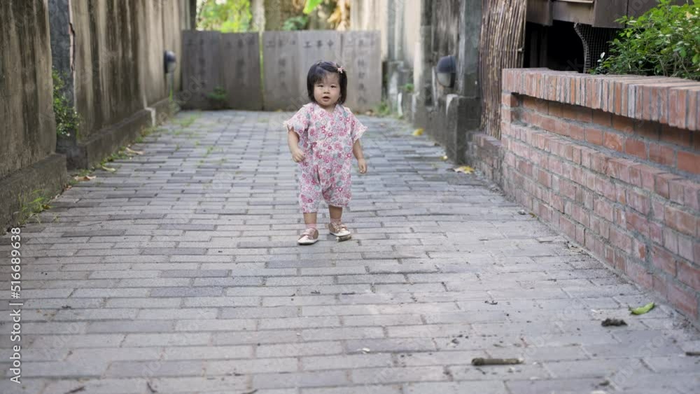 front view with full length asian toddler girl in kimono is waving hands feeling upset about dropping the bark as she lifts it up to show someone in distance. front view with full length asian toddler girl in kimono is waving hands feeling upset about dropping the bark as she lifts it up to show someone in distance.