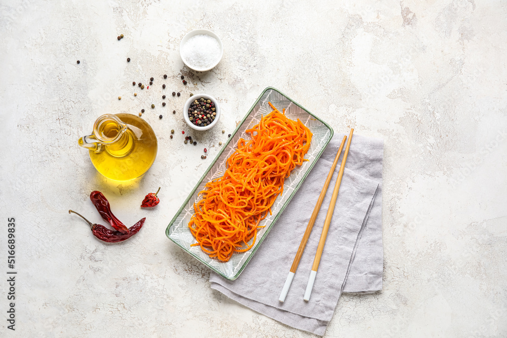Composition with bowl of tasty korean carrot salad and ingredients on light background Composition with bowl of tasty korean carrot salad and ingredients on light background