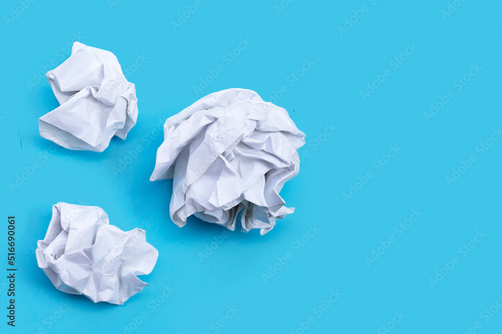 White crumpled paper on blue background. Ideas and creative thinking concept. Top view White crumpled paper on blue background. Ideas and creative thinking concept. Top view