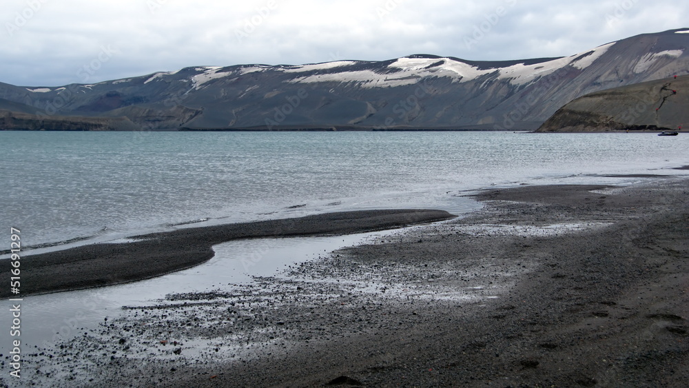 Snow dusted rim of a volcanic crater, filled with water to form a bay, at Telefon Bay, Deception Island, Antarctica