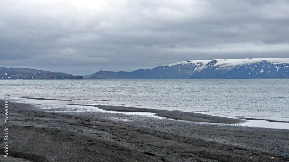 Snow dusted rim of a volcanic crater, filled with water to form a bay, at Telefon Bay, Deception Island, Antarctica