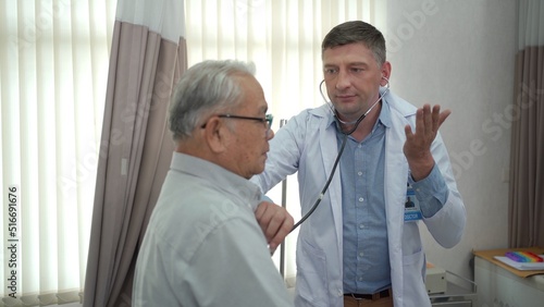 Asian elder adult having a consult with doctor about his disease, doctor checks respiratory system.