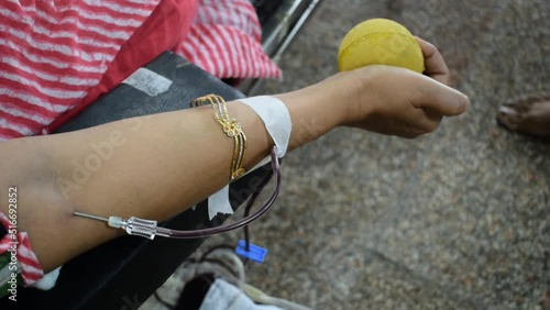 Blood donor at Blood donation camp held with a bouncy ball holding in hand at Balaji Temple, Vivek Vihar, Delhi, India. Also concept image for World blood donor day on June 14 every year photo