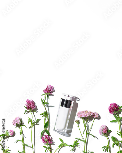 Cosmetic container  white pump bottle  cream with medical herbs  wild flowers isolated white background. Blank label package for branding mock up. Natural organic beauty product concept