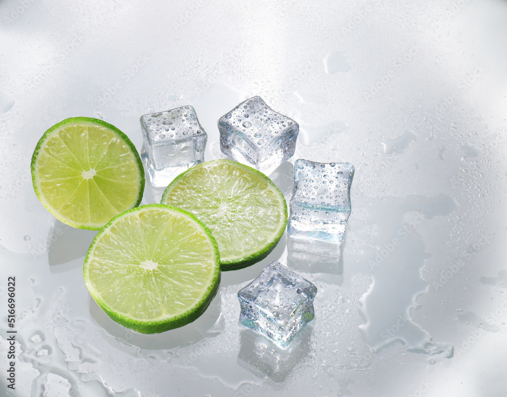 The green lemon is blank with a cut piece showing the inside of the citrus zest. The clear glass reflects the shadows of the lemon and the wet water, giving it freshness and ice adding cooling. The green lemon is blank with a cut piece showing the inside of the citrus zest. The clear glass reflects the shadows of the lemon and the wet water, giving it freshness and ice adding cooling.