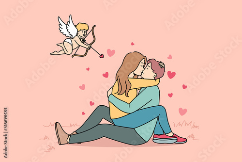 Cupid shooting with arrows in to happy couple kissing. Woman sitting on man hugging and cuddling. Love and relationship. Vector illustration. 