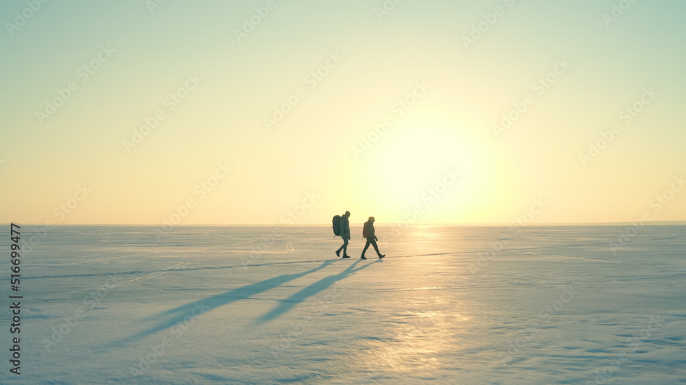 The two people with backpacks going through the snow field