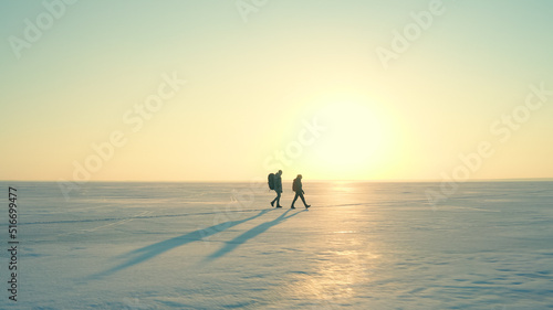 The two people with backpacks going through the snow field