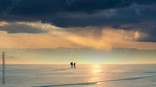 The two people with backpacks going through the snow field