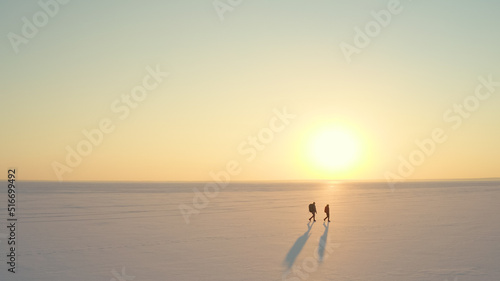 The two people with backpacks going through the snow field against beautiful sky © Artem
