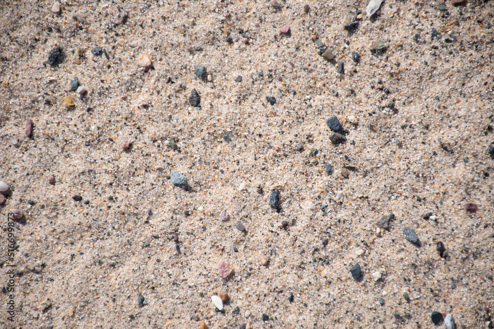 Sandy beach: background of the bathing season or industry for the extraction and sifting of sand, sand with stone inclusions, background, texture of nature Sandy beach: background of the bathing season or industry for the extraction and sifting of sand, sand with stone inclusions, background, texture of nature