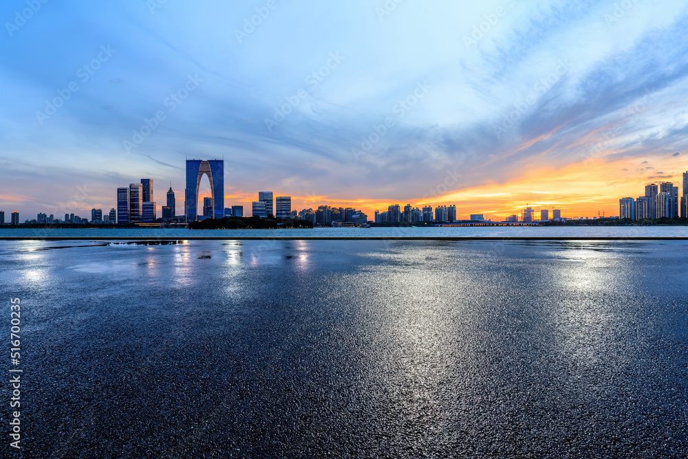 Asphalt road and city skyline with modern building at sunset in Suzhou, China. 