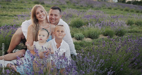 Portrait of a happy family with two children sitting on a blooming lavender field
