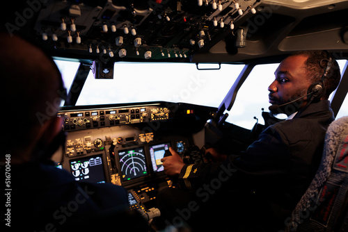 African american pilot flying aircraft jet doing teamwork with captain, using dashboard command and navigation. Team of airliners pushing control panel buttons and lever to takeoff and fly.