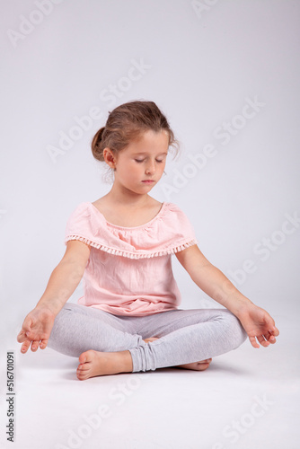 Cute young girl practice meditation sitting in crossed legs lotus postition with closed eyes.