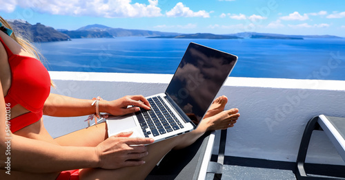 Close up of woman hand with nomad digital freelancer as running remotely with bright scenic view of the Mediterranean Sea ,Oia -Santorini,Greece
