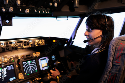 Aircrew member flying plane from cockpit with dashboard command and control panel, using steering wheel and control panel for windscreen navigation. Woman using lever to fly aircraft.