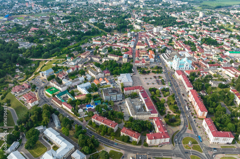 Obraz premium aerial panoramic view from great height on red roofs of old big city with skyscrapers and white fluffy clouds