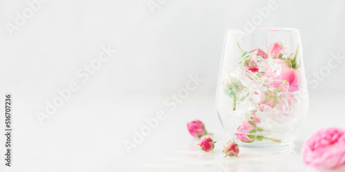 Frozen roses in ice cubes  in glass on white background.