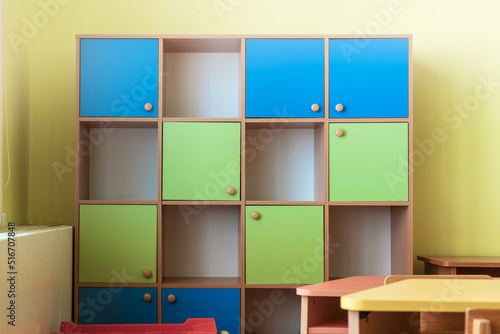 Multi colored wooden cabinet with cells stands in empty classroom. School and kindergarten furniture. photo