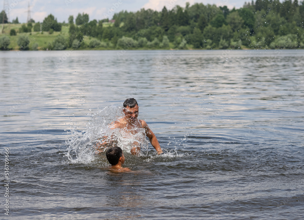 father and son swim in a pond