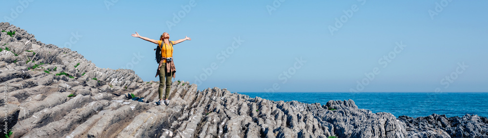 Young woman raising arms hiking through flysch rock landscape. Freedom concept Young woman raising arms hiking through flysch rock landscape. Freedom concept